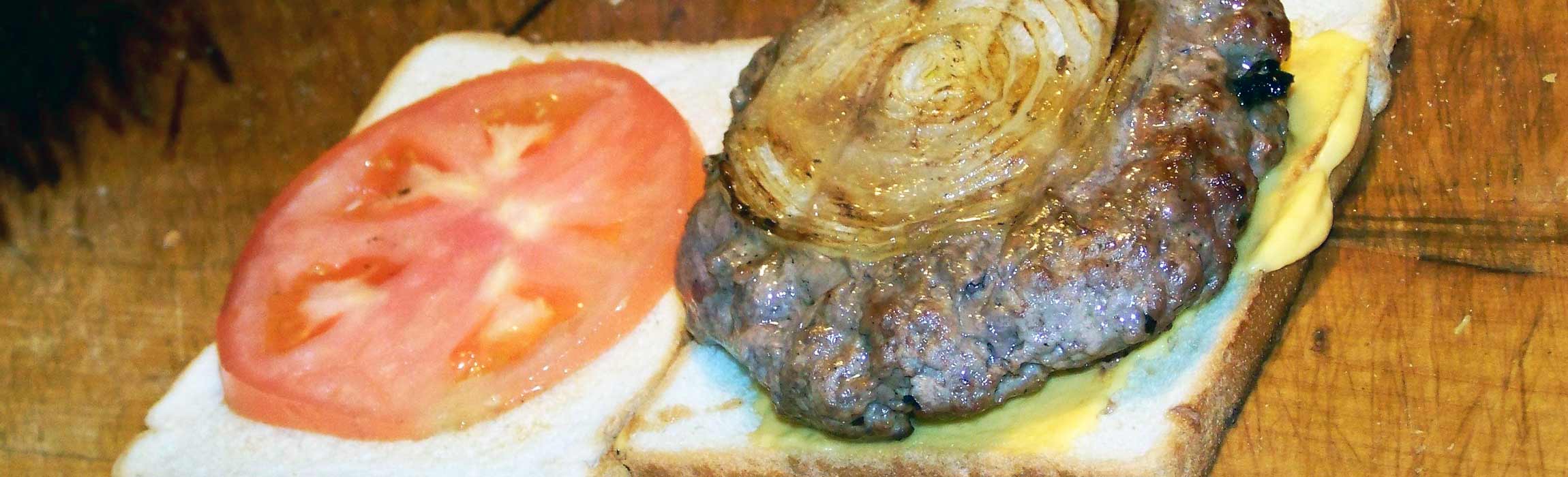 Burger patty with onion, tomato, and cheese from Louis' Lunch restaurant in New Haven, CT